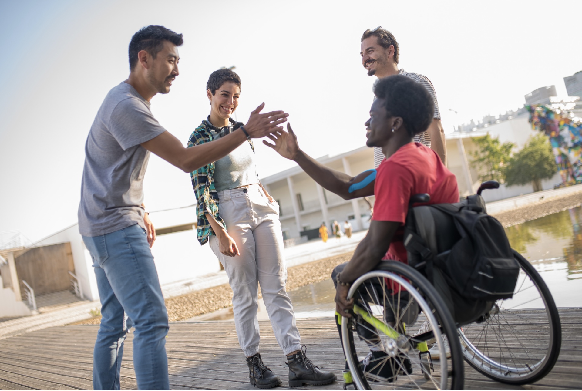 Wheelchair user outdoors with support workers
